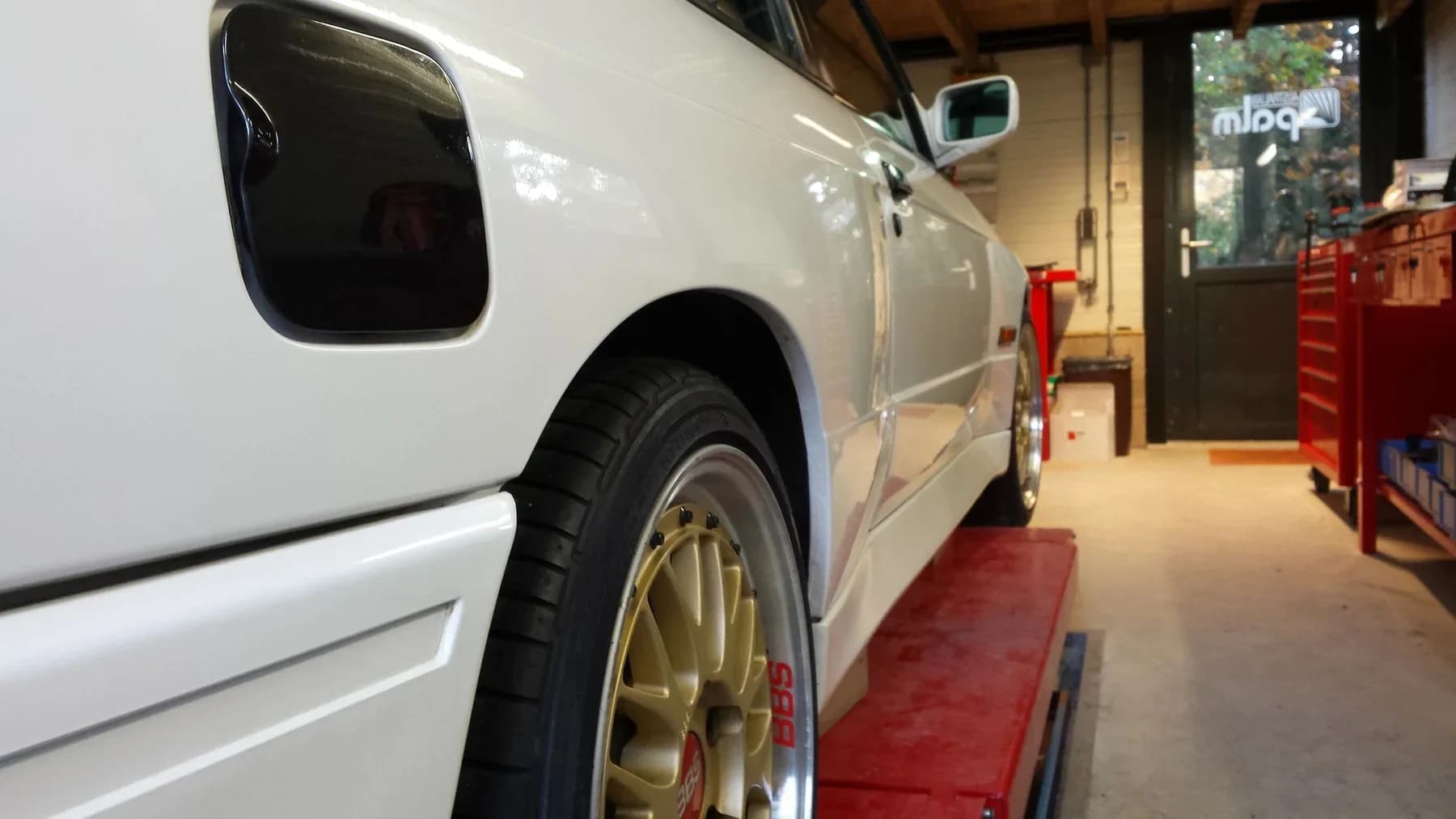 Witte auto met een opvallende goudkleurige velg.